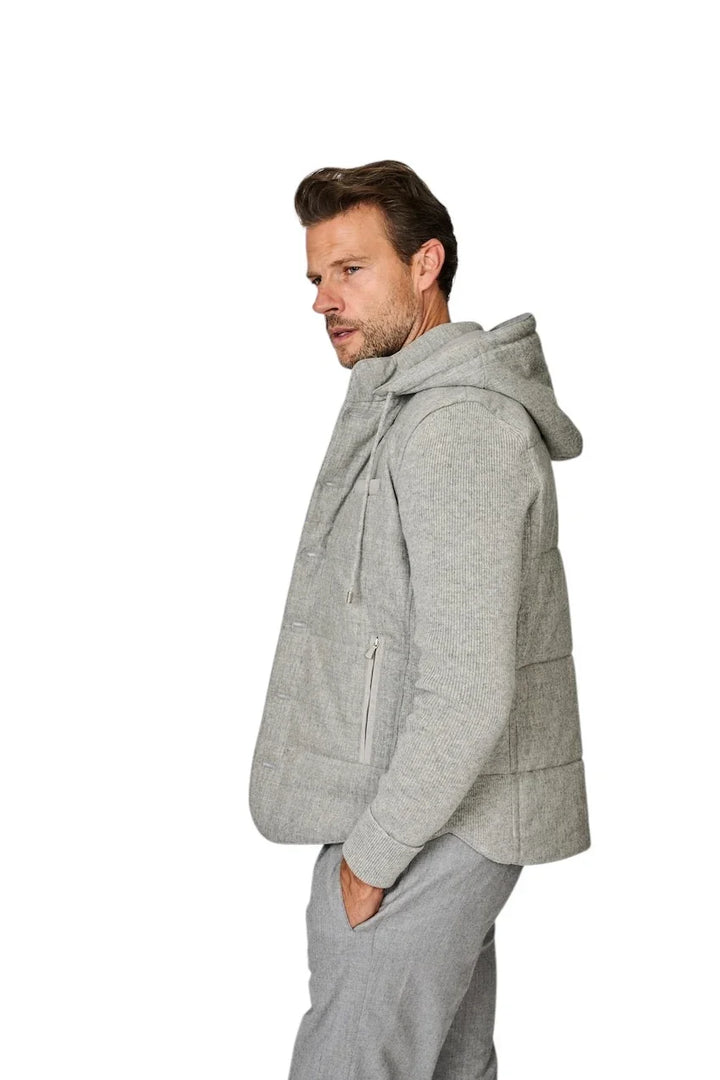 Man in een lichtgrijze gewatteerde jas met capuchon en bijpassende grijze broek