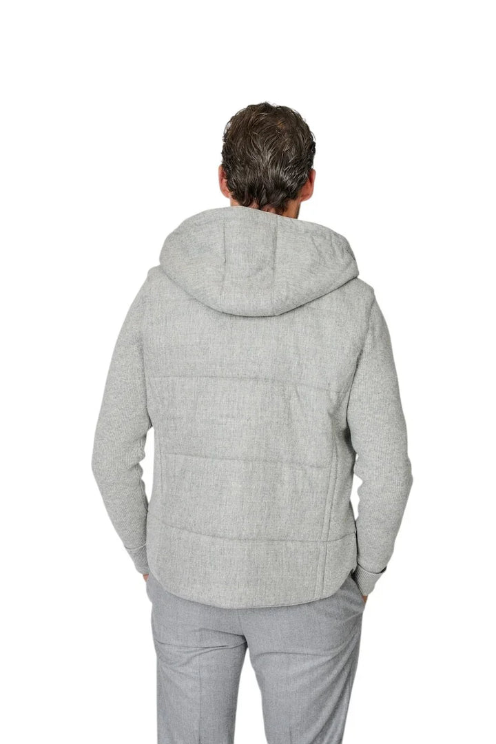 Man van achteren met een grijze gewatteerde jas met capuchon en grijze broek.