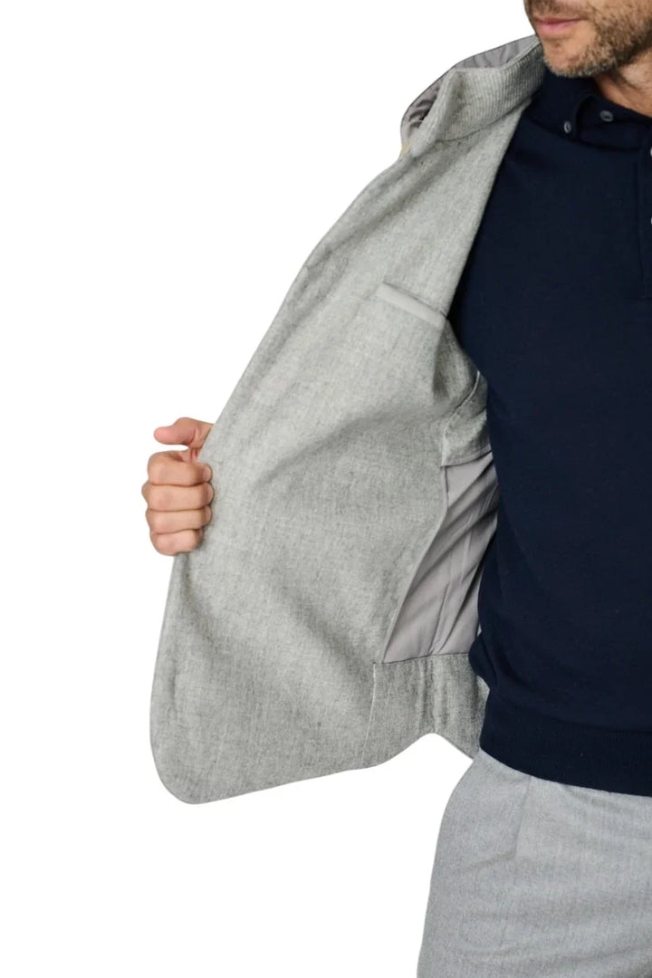 Man in lichtgrijs herenjasje met donkerblauwe polo en grijze pantalon