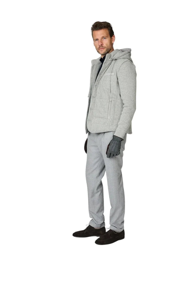 Man in grijze hooded jas, grijze pantalon en donkere handschoenen.