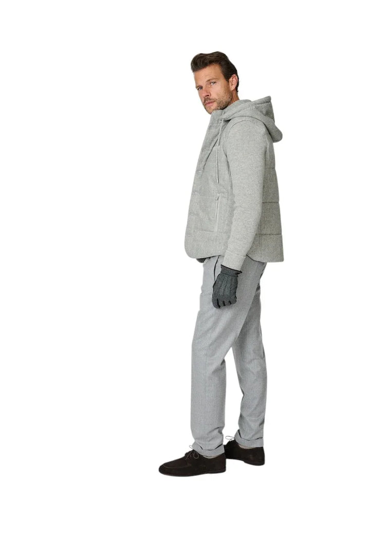 Man in grijze hoodie, gewatteerd vest en grijze broek met handschoenen.