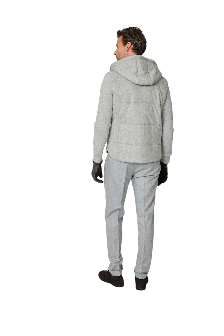 Man in een grijze gewatteerde hoodie en lichtgrijze herenpantalon.