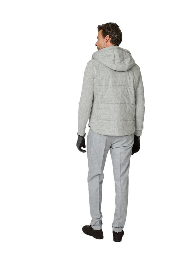 Man in een grijze gewatteerde hoodie en lichtgrijze herenpantalon.