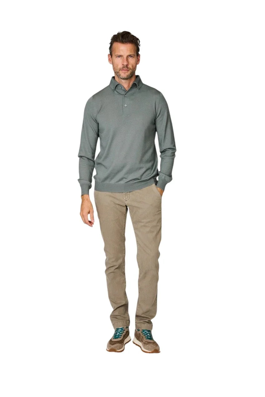 Man in een grijsgekleurde polo met lange mouwen en een beige chino broek.