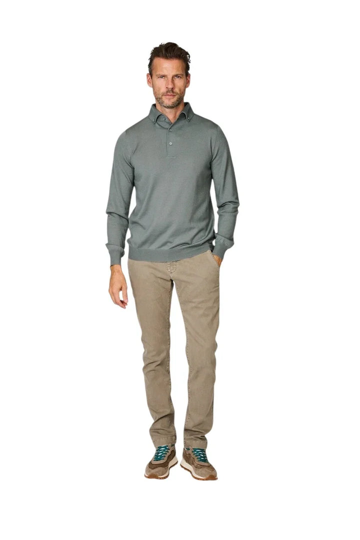 Man in een grijsgekleurde polo met lange mouwen en een beige chino broek.
