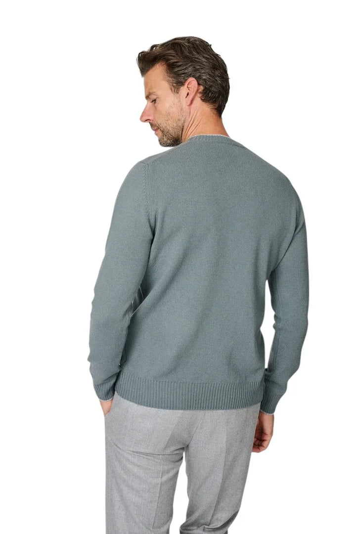 Man van achteren in een grijsblauwe gebreide trui en een lichtgrijze pantalon.