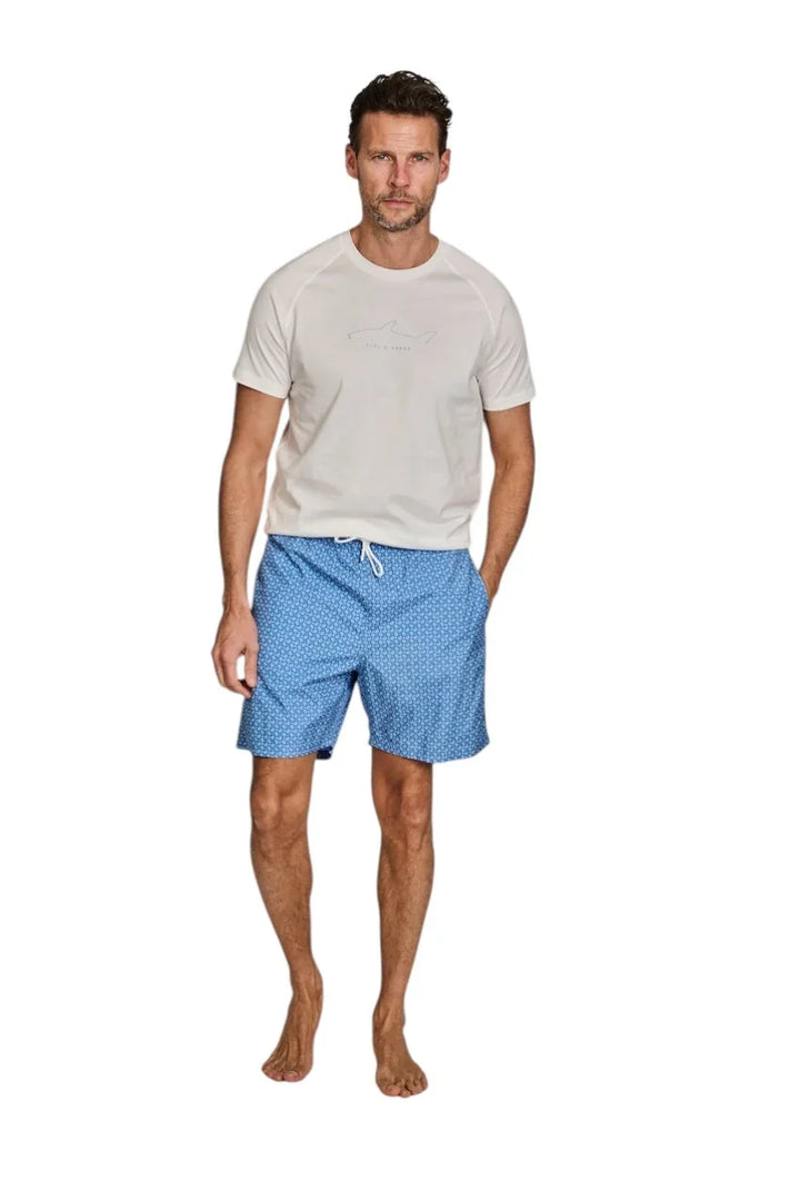 Man in wit T-shirt en blauwe zwembroek met witte stippen.