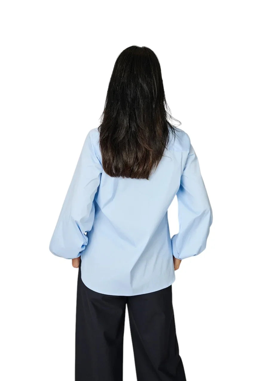 Lichtblauwe dames blouse met lange mouwen en zwarte broek, achterzijde