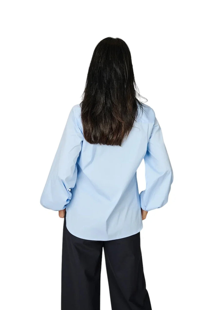 Lichtblauwe dames blouse met lange mouwen en zwarte broek, achterzijde