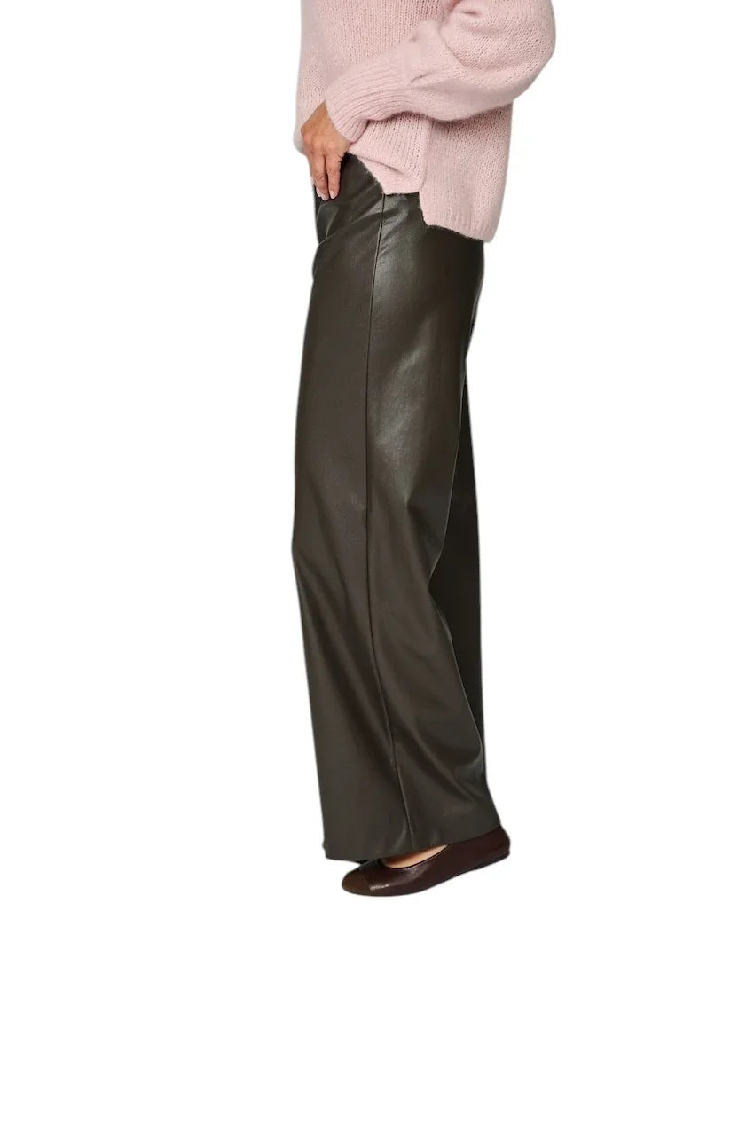 Damesmodel in een donkergrijze leren wijde broek en een roze gebreide trui.