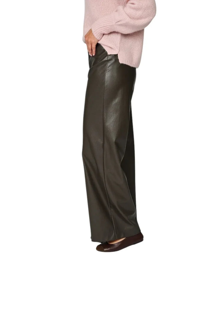 Damesmodel in een donkergrijze leren wijde broek en een roze gebreide trui.