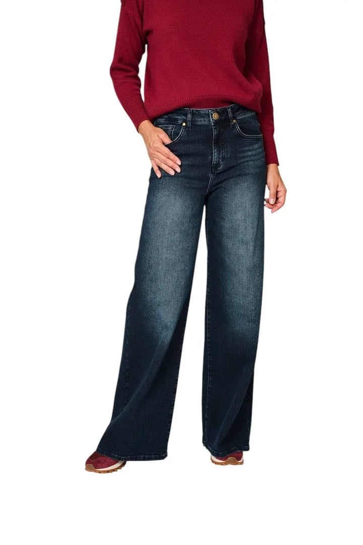 Damesmodel in een donkerblauwe wide leg jeans en een rode trui.