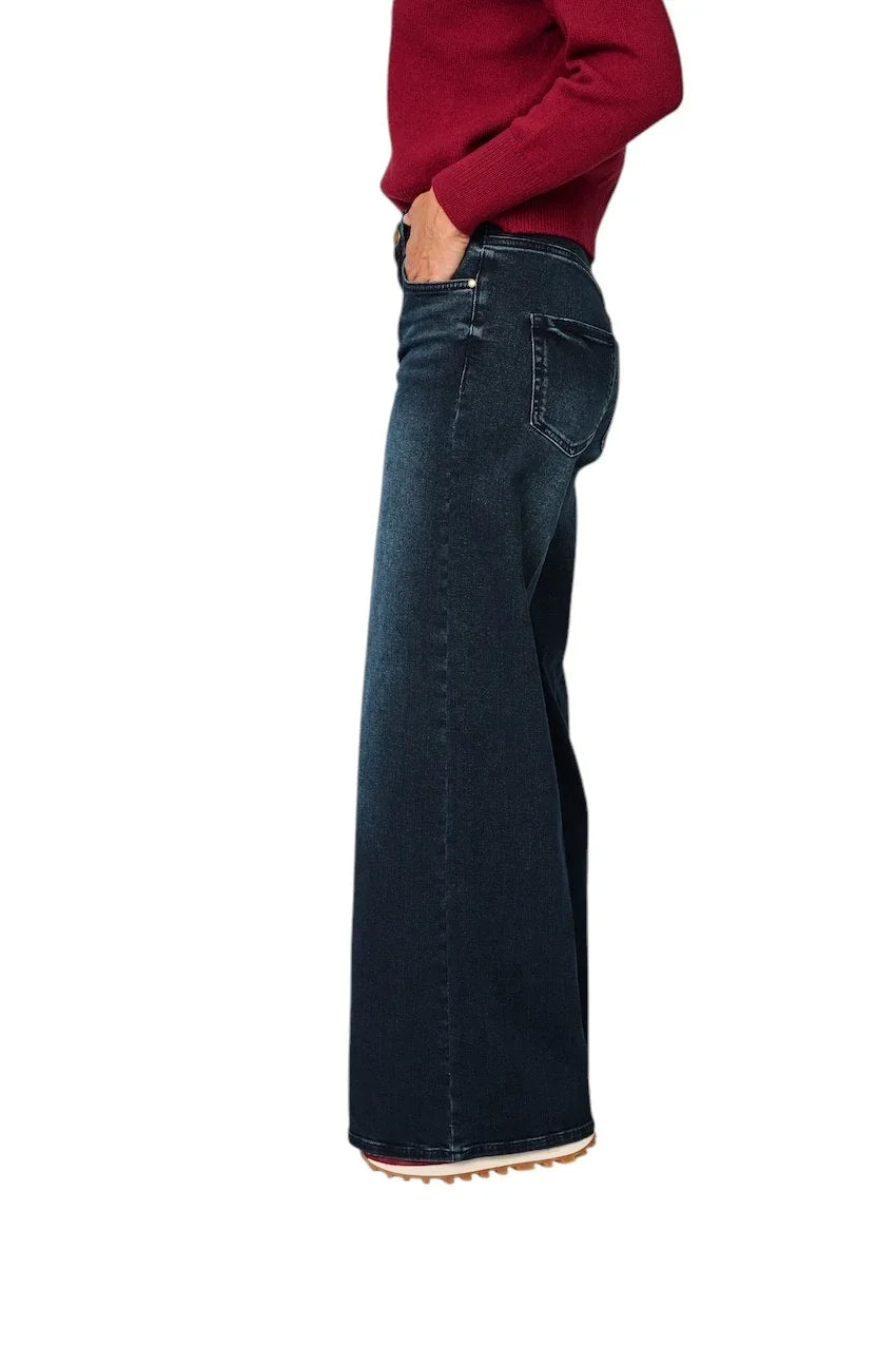 Dama in een donkerblauwe wijde jeans en een rode trui